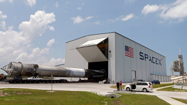 Eine geborgene Falcon-Rakete wird aus einem Hangar transportiert. Eine geborgene Falcon-Rakete wird aus einem Hangar transportiert.