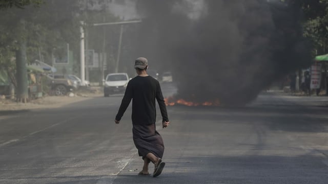 Mann läuft auf Strasse. Es brennt ein Feuer darauf. Viel Rauch. Mann läuft auf Strasse. Es brennt ein Feuer darauf. Viel Rauch.