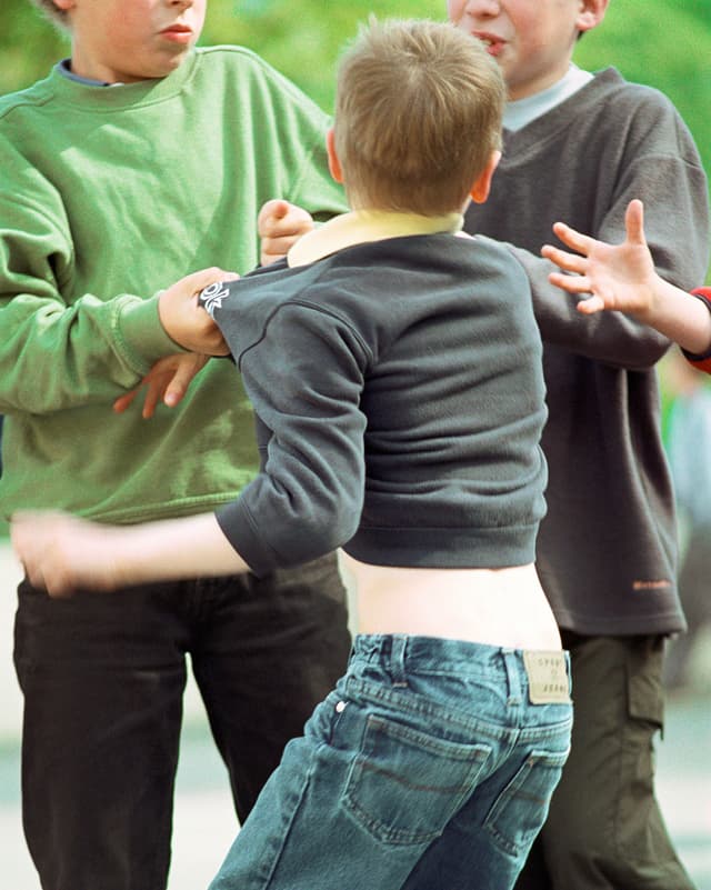 Zwei Jungen attackieren einen dritten Jungen. Zwei Jungen attackieren einen dritten Jungen.