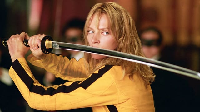 Frau trägt gelben Anzug und Schwert. 