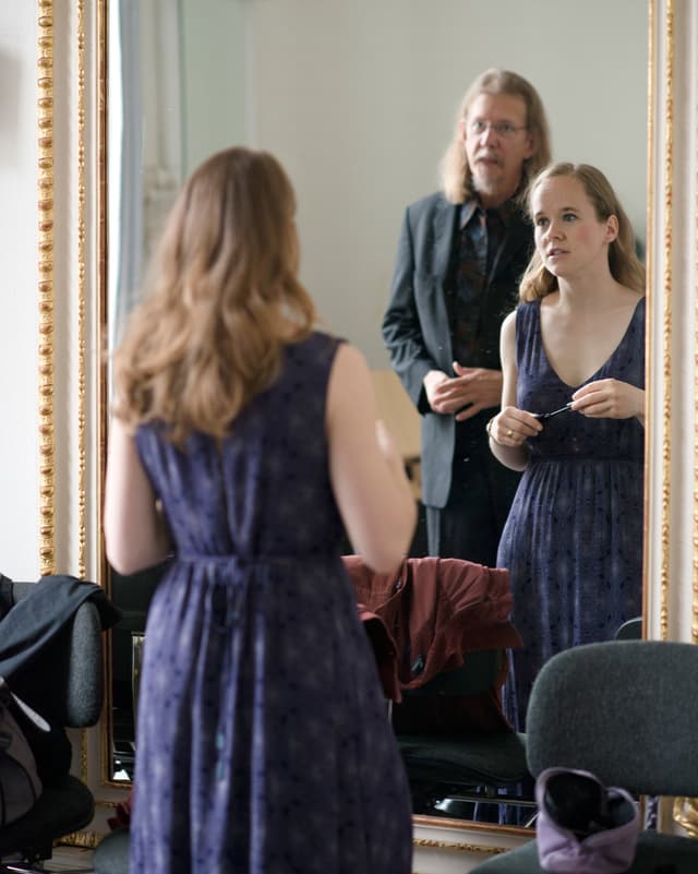 Eine Frau in einem eleganten Kleid und ein Herr vor einem grossen Spiegel. Eine Frau in einem eleganten Kleid und ein Herr vor einem grossen Spiegel.