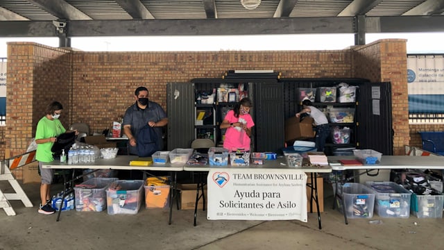 Stand des «Teams Brownsville» mit vier Personen und Kleidungsstücken und anderen Dingen für die Migranten. Stand des «Teams Brownsville» mit vier Personen und Kleidungsstücken und anderen Dingen für die Migranten.