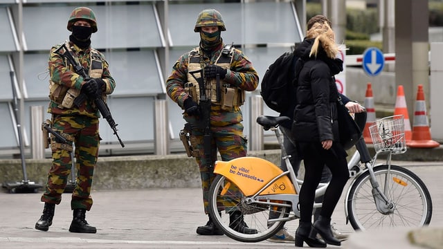 Zwei bewaffnete Militaristen bewachen nach den Anschlägen in Brüssel ein Gebäude. Zwei bewaffnete Militaristen bewachen nach den Anschlägen in Brüssel ein Gebäude.