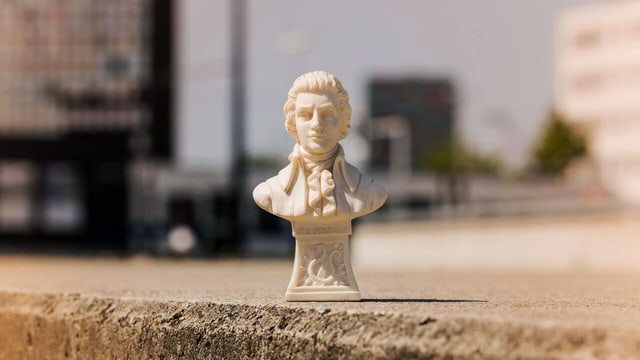 Eine fausthohe Mozartfigur auf einer Mauer platziert. Eine fausthohe Mozartfigur auf einer Mauer platziert.