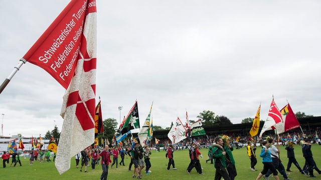 Fahnenschwinger laufen in einer Reihe durch ein offenes Stadion Fahnenschwinger laufen in einer Reihe durch ein offenes Stadion