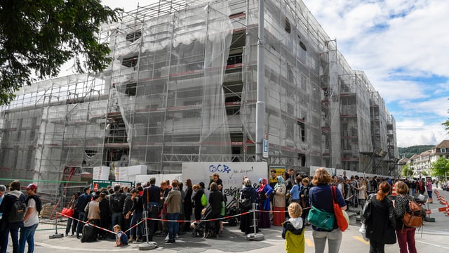 Hunderte Menschen stehen bei einer Baustelle für eine neue Wohnung an Hunderte Menschen stehen bei einer Baustelle für eine neue Wohnung an