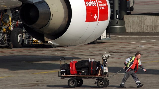 Mitarbeiter zieht Wagen mit Koffern. Mitarbeiter zieht Wagen mit Koffern.