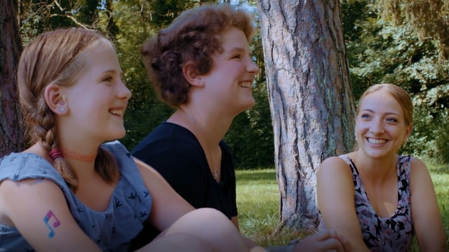 Tamara, Noémi und Anna Zöllig sitzen auf einer Wiese. Tamara, Noémi und Anna Zöllig sitzen auf einer Wiese.