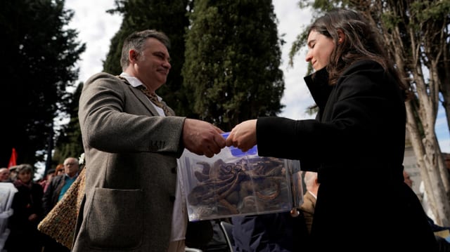Mann übergibt einer Frau eine Plastik-Box mit menschlichen Knochen Mann übergibt einer Frau eine Plastik-Box mit menschlichen Knochen