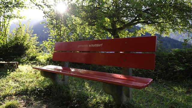 Bank mit Aufschrift Gemeinde Schattdorf. Es ist sonnig, aber die Bank ist im Schatten. Bank mit Aufschrift Gemeinde Schattdorf. Es ist sonnig, aber die Bank ist im Schatten.