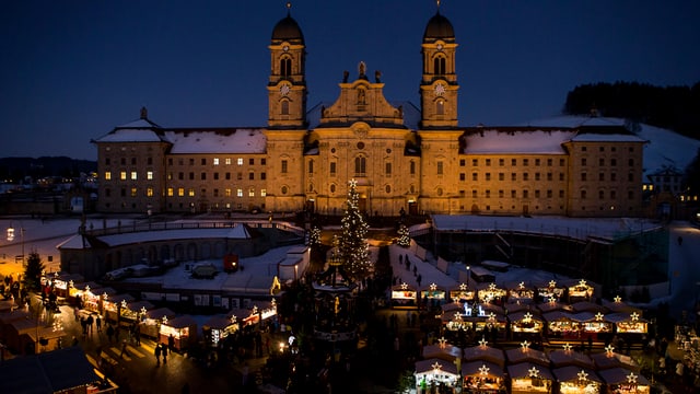 Ein grosses Kloster, davor leuchten die Lichter eines Weihnachtsmarktes. Ein grosses Kloster, davor leuchten die Lichter eines Weihnachtsmarktes.