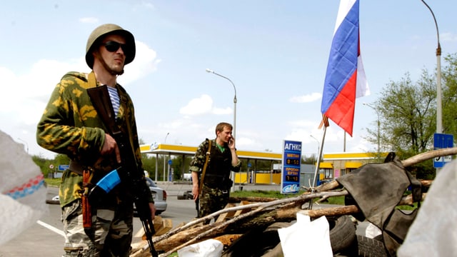 Ein pro-russischer Separatist steht an einer Strassensperre. Ein pro-russischer Separatist steht an einer Strassensperre.