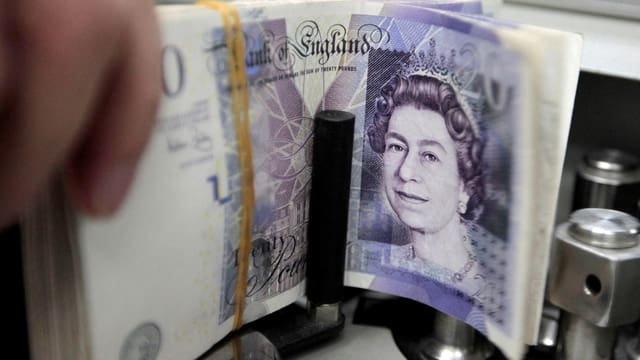 Bündel Pfundnoten in einer Geldzählmaschine, gut sichtbar der Kopf der Queen auf der Note Bündel Pfundnoten in einer Geldzählmaschine, gut sichtbar der Kopf der Queen auf der Note
