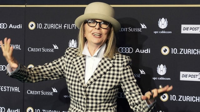 Frau mit kariertem Jacket und Hut und Hornbrille vor der Fotowand des Zurich Film Festivals. Frau mit kariertem Jacket und Hut und Hornbrille vor der Fotowand des Zurich Film Festivals.
