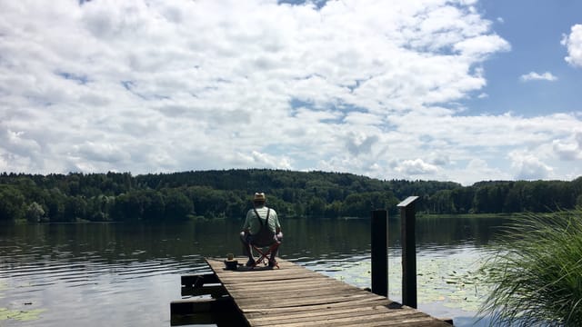 Fischer auf Steg an See