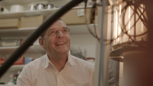Auf dem Bild ist Hansjürg Leibundgut zu sehen wie er einen technischen Apparat betrachtet. Auf dem Bild ist Hansjürg Leibundgut zu sehen wie er einen technischen Apparat betrachtet.