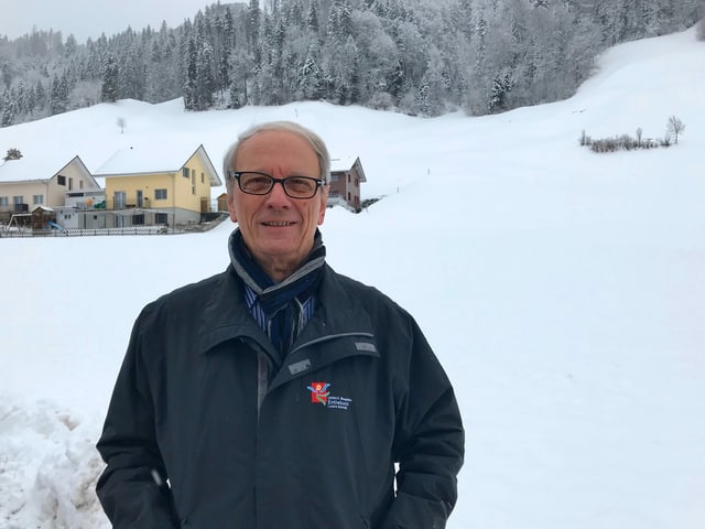 Ein Mann in dunkler Jacke vor einer verschneiten Wiese. Ein Mann in dunkler Jacke vor einer verschneiten Wiese.