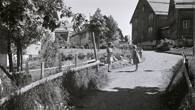 eine schwarz-weiss Fotografie von zwei Kindern inmitten Häusern und Garten eine schwarz-weiss Fotografie von zwei Kindern inmitten Häusern und Garten