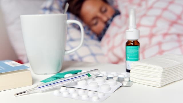 Jemand liegt im Bett, im Vordergrund Medikamente. Jemand liegt im Bett, im Vordergrund Medikamente.