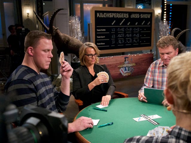 Matthias Sempach und Sonja Hasler am Jasstisch mit Jasskarten in der Hand
