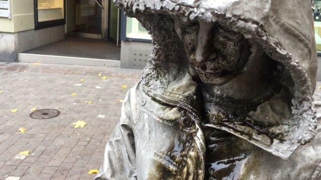 Skulptur einer Frau, die einen Kapuzenmantel trägt und weint. Skulptur einer Frau, die einen Kapuzenmantel trägt und weint.
