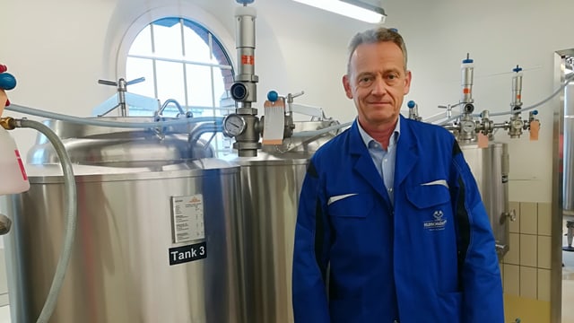 Ein Mann steht vor mehreren Metalbehältern Ein Mann steht vor mehreren Metalbehältern