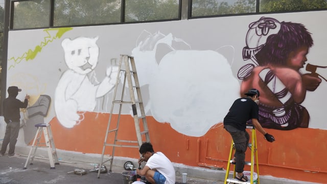 Malen von Graffiti an einer Hausmauer Malen von Graffiti an einer Hausmauer