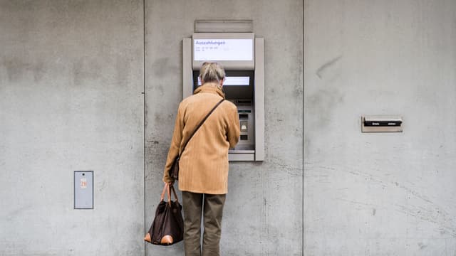 Eine Frau bezieht Geld an einem Bankomat. Eine Frau bezieht Geld an einem Bankomat.