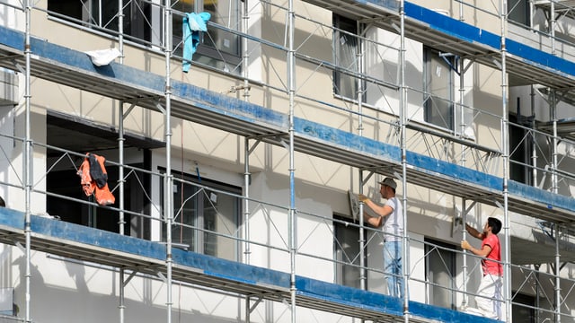 Bauarbeiter arbeiten auf einem Baugerüst an einer Fassade Bauarbeiter arbeiten auf einem Baugerüst an einer Fassade