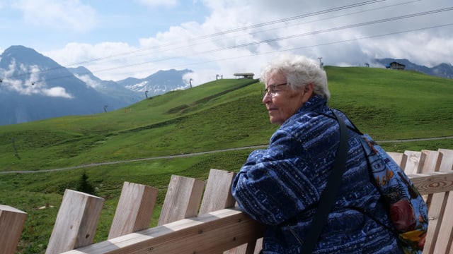 Ältere Frau steht an einem Zaun Ältere Frau steht an einem Zaun
