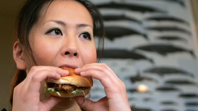 Frau isst einen Walburger. Frau isst einen Walburger.