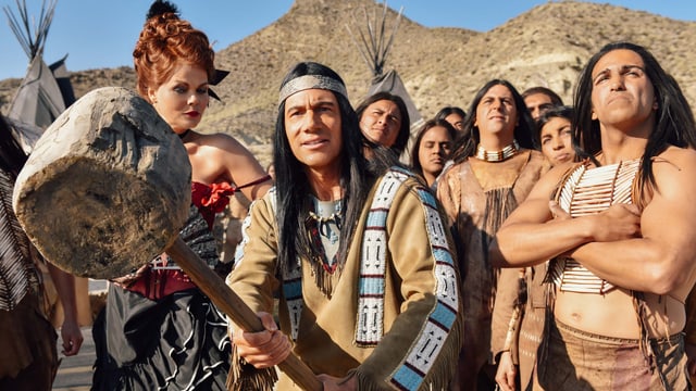 Bully als Winnetou, in der Hand ein riesiger Holzhammer, umgeben von anderen Indianern und einer Frau Bully als Winnetou, in der Hand ein riesiger Holzhammer, umgeben von anderen Indianern und einer Frau