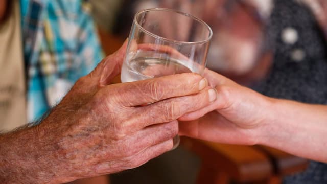 Zwei Hände an einem Wasserglas Zwei Hände an einem Wasserglas