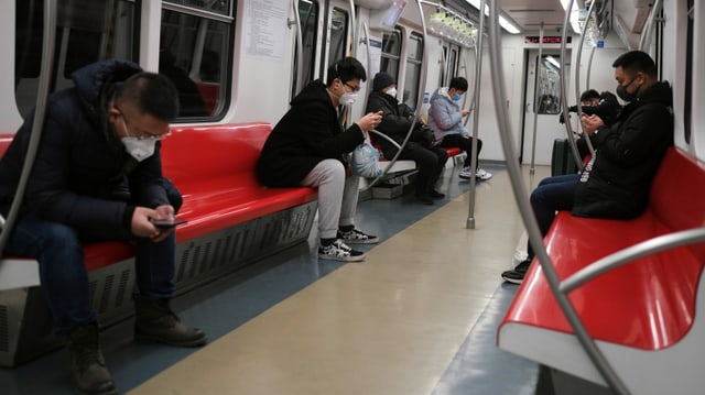 Personen mit Schutzmasken in einer Metro sitzend. Personen mit Schutzmasken in einer Metro sitzend.