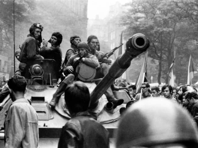 Panzer in einer Menschenmenge, darauf sitzen Soldaten Panzer in einer Menschenmenge, darauf sitzen Soldaten