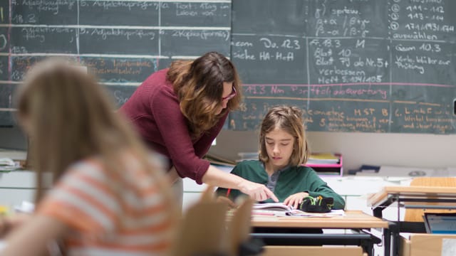 Lehrerin im Schulzimmer mit Kindern Lehrerin im Schulzimmer mit Kindern