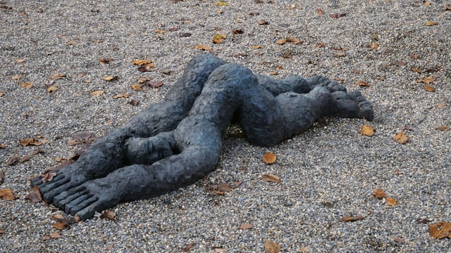 Eine Figur aus Stein liegt am Boden. Eine Figur aus Stein liegt am Boden.