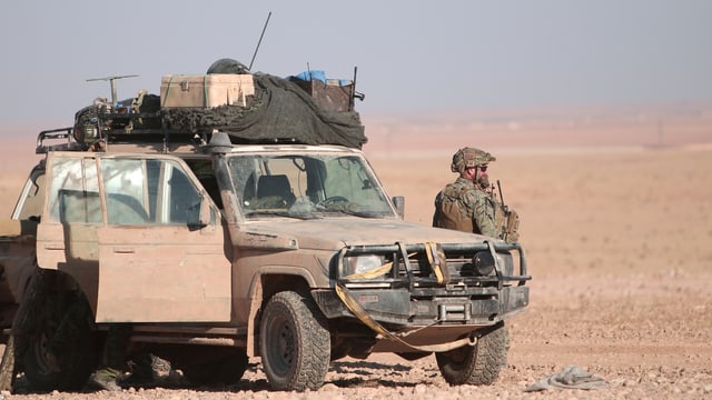Jeep in der Wüste, daneben steht ein Mann in Kampfmontur. Jeep in der Wüste, daneben steht ein Mann in Kampfmontur.