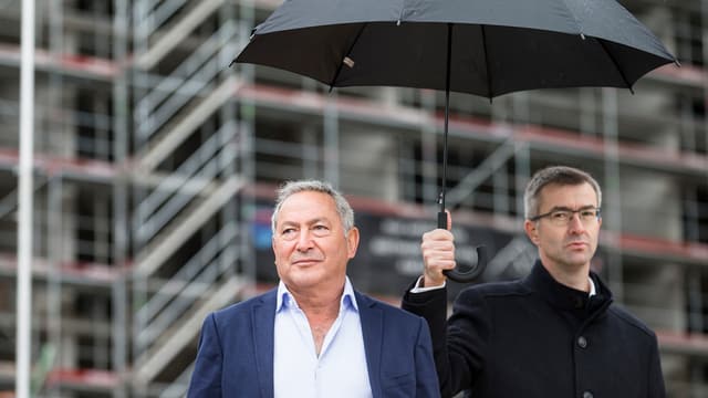 Samih Sawiris und ein Mann stehen unter einem Regenschirm. Samih Sawiris und ein Mann stehen unter einem Regenschirm.