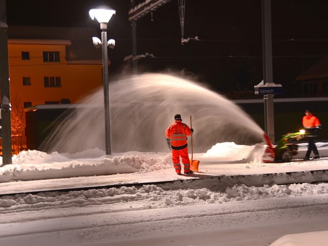 Arbeiter beim Schnee Räumen auf dem Bahnsteig.