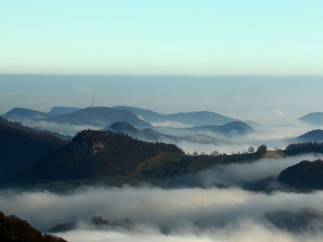 Hüglige Landschaft mit Nebelschwaden in den Tälern.