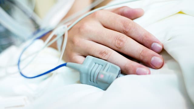 Eine Hand auf dem Spitalbett. Sie ist verkabelt. Eine Hand auf dem Spitalbett. Sie ist verkabelt.