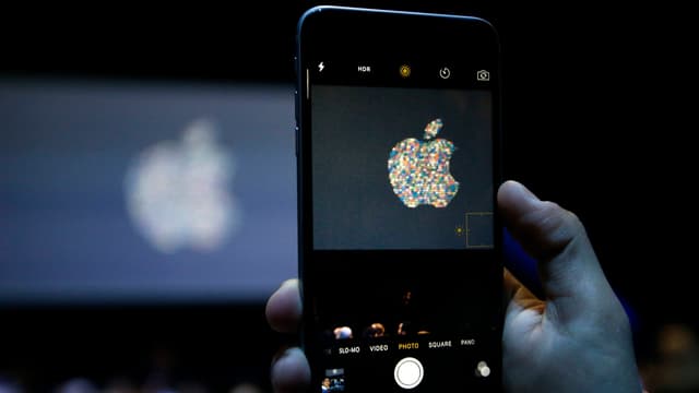 Hand hält iPhone in die Höhe und drückt auf Startknopf. Hand hält iPhone in die Höhe und drückt auf Startknopf.
