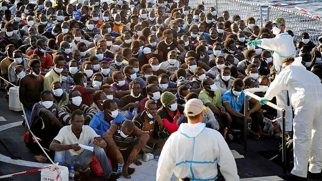 Helfer mit zahlreichen Bootsflüchtlingen Helfer mit zahlreichen Bootsflüchtlingen