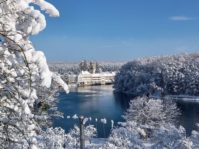 Blick auf Fluss mit viel Schnee am Ufer und Kloster