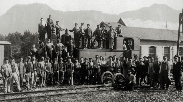 Altes schwarz-weiss Bild von einer grossen Gruppe Eisenbahnarbeitern die auf einer Lock fürs Foto posieren Altes schwarz-weiss Bild von einer grossen Gruppe Eisenbahnarbeitern die auf einer Lock fürs Foto posieren