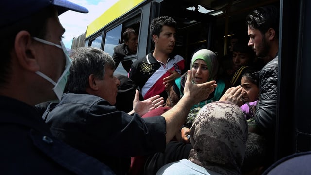 Flüchtlinge in Piräus werden in einen Bus gewiesen.