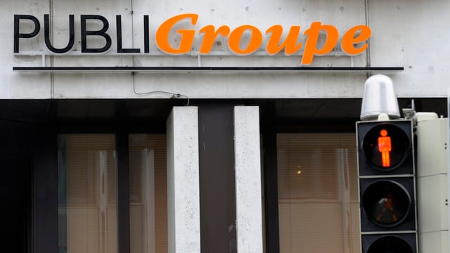 Leuchtreklame der Publigroupe. Vorne dran eine Fussgängerampel auf rot. Leuchtreklame der Publigroupe. Vorne dran eine Fussgängerampel auf rot.