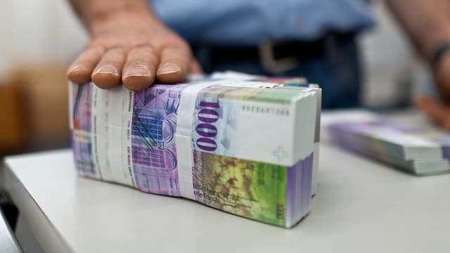 Ein grosses Bündel 1000er Noten, ein Mann hält seine Hand darauf. Ein grosses Bündel 1000er Noten, ein Mann hält seine Hand darauf.