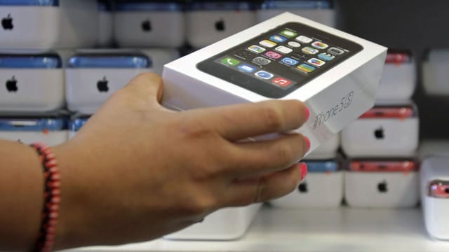 Ein Mann nimmt eine iPhone5s-Verpackung aus dem Regal Ein Mann nimmt eine iPhone5s-Verpackung aus dem Regal